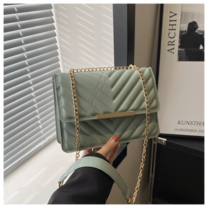 Detail of pea green quilted crossbody bag with golden chain and metallic buckle