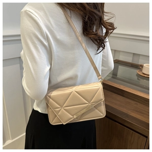 Close-up of beige quilted crossbody bag with geometric stitching and gold metal bar