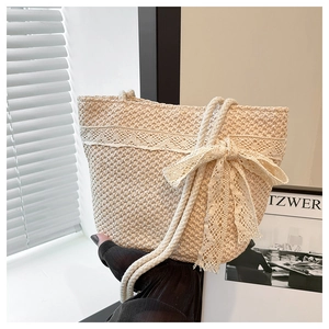 Detail of hand-woven straw tote bag with elegant lace trim and large decorative bow detail