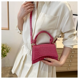 Detail view of fuchsia crocodile pattern handbag with unique curved base and knotted handle