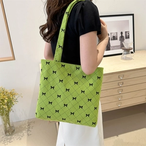 Borsa tote in maglia verde con motivi a fiocco nero indossata a spalla lateralmente