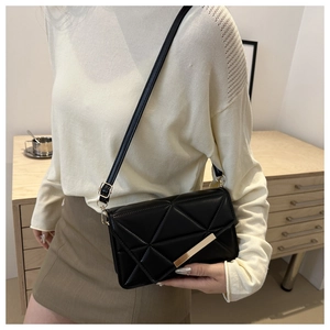 Close-up of black crossbody bag with geometric stitching and gold bar hardware detail