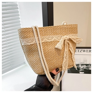 Detail of woven straw tote bag featuring delicate lace bow and soft cotton rope handles