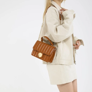 Caramel brown quilted small tote bag with gold chain strap shown on a fashion model