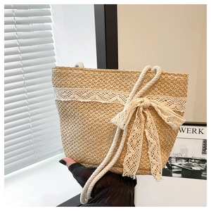 Close-up of woven straw tote bag featuring elegant white lace bow and sturdy cotton rope handle