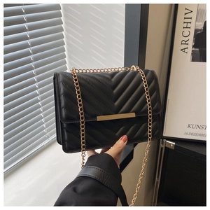 Detail of black V-quilted faux leather bag with gold metal trim and elegant chain strap