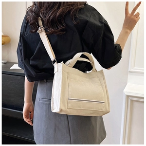 Rear view of model wearing a cream canvas tote bag with adjustable shoulder strap