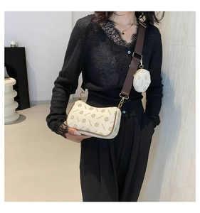 Detail of cream crossbody dumpling bag with signature pattern and mini coin purse charm