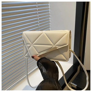 Detail of white quilted leather crossbody bag featuring a golden metal buckle and slim strap