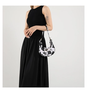 Cow print crescent shoulder bag on a model wearing a black dress in a studio