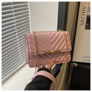 Detail of pink quilted shoulder bag featuring gold chain strap and metal clasp closure