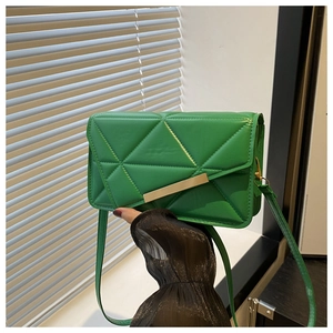 Detail of emerald green quilted crossbody bag with golden hardware and PU texture