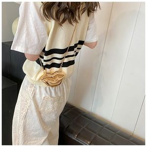 Detailed view of the metallic gold lip-shaped crossbody bag with slim chain strap