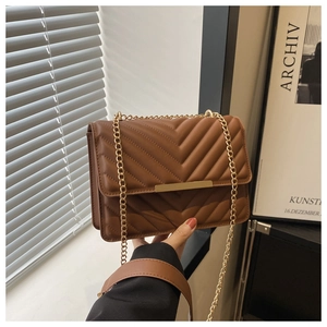 Detailed view of brown quilted leather bag with V-shaped pattern and gold chain strap