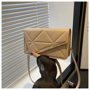 Close-up of beige geometric crossbody bag with gold metal trim and textured PU leather finish