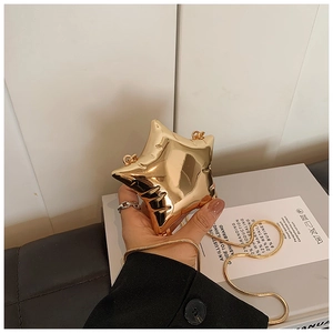 Close-up of a metallic gold star-shaped mini bag with a thin snake chain strap
