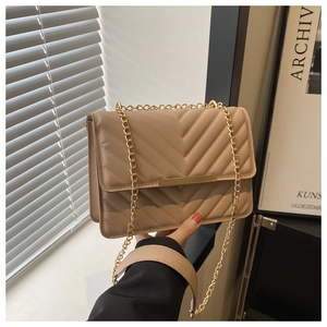 Detailed close-up of beige chevron quilted leather crossbody bag with gold chain strap