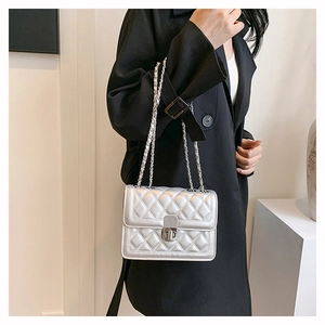 Detail showing silver quilted crossbody bag with metal chain strap on female model