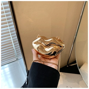 Macro shot of creative gold lip-shaped handbag featuring high-gloss metallic finish