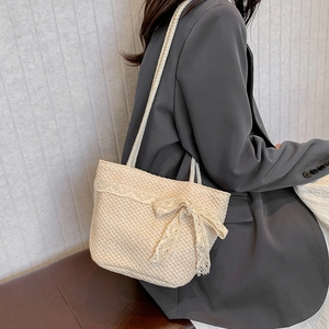 Large capacity woven tote bag with lace bow handle shown on model in minimal studio