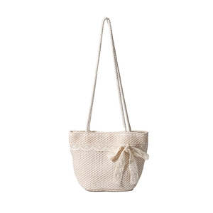 Handwoven straw shoulder bag with lace trim and large bow for seaside beach vacations