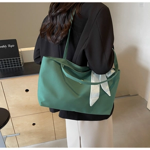 Forest green tote bag with plaid scarf detail shown on shoulder in a minimalist setting