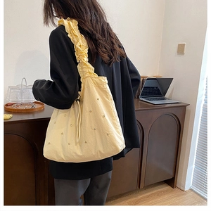 Detail van beige stoffen emmertas met brede ruches schouderband en parelaccenten