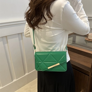 Fashionable green quilted leather crossbody bag with gold metal clasp on female model