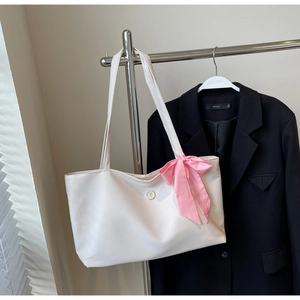 Detailed view of white tote bag with embossed B logo and pink checkered bow accent
