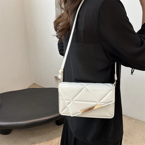 Minimalist white crossbody bag with geometric quilting and gold trim shown on model