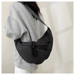Dettaglio della borsa a mezzaluna in nylon nero con design pieghettato e cordino zip
