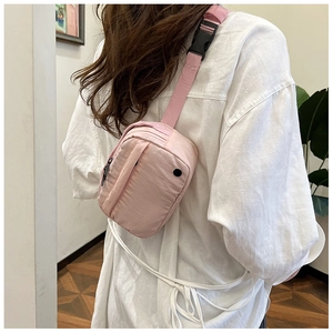 Back view of a woman wearing a pink nylon crossbody chest bag over a white shirt