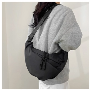 Vista laterale della grande borsa a mezzaluna in nylon nero su modella con zip intrecciata
