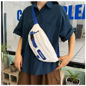 Detail of blue and white crossbody bag featuring woven strap and buckle on model