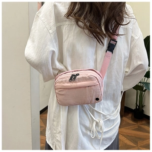 Detailed back view of pink nylon crossbody bag worn on casual outfit showing texture