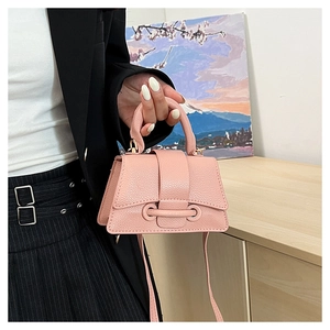Detail of pink mini trapezoid crossbody bag with lychee grain texture and gold hardware