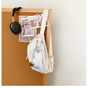 Detail of white chest bag with colorful embroidery and star charms on cork board