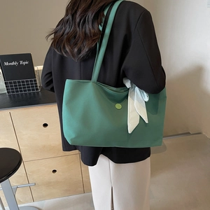 Green canvas tote bag with check ribbon and letter E logo for minimalist daily commuting