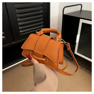 Detailed view of bright orange crossbody bag featuring premium lychee pattern leather texture