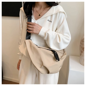 Dettaglio della borsa a tracolla beige a mezzaluna con cerniera e cordino intrecciato