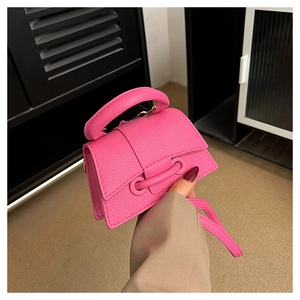 Detail of fuchsia leather handbag with grain texture and circular buckle accent