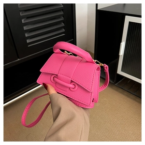 Mini magenta crossbody bag with litchi texture held in hand showing compact size