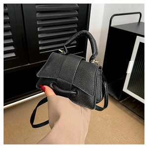 Detail of black mini handbag showing lychee pattern leather and unique perforated front design