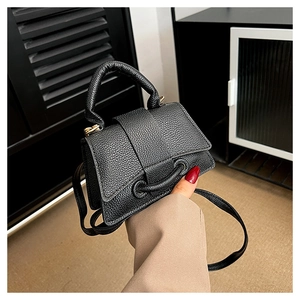 Detail of black mini crossbody bag featuring pebbled leather texture and structured flap design