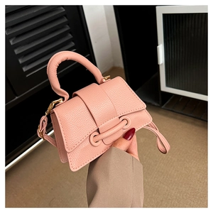Detail of lychee textured pink crossbody bag with reinforced handle and gold metal hardware