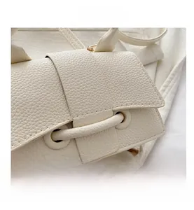 Close-up of creamy white lychee grain leather handbag with gold hardware and drawstring detail