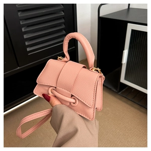 Detailed macro view of salmon pink crossbody bag with textured pebble grain leather and gold hardware