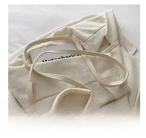 Detail of minimalist beige pebble leather crossbody bag with adjustable strap and gold hardware