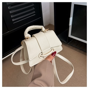 Detail of creamy white litchi pattern leather bag with gold hardware and top handle