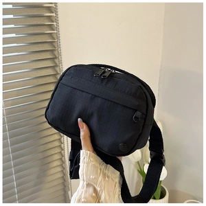 Detail of black ripstop nylon texture and metal zipper on functional crossbody bag
